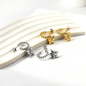 Close-up of golden and silver butterfly pendant earrings with beaded texture detail