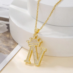 Macro shot of gold crown initial N necklace pendant with sparkling paved zircon stones