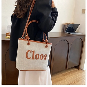 Detail of canvas tote bag with brown leather trim and knotted handle design