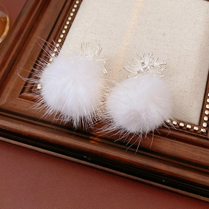 Macro shot of white fur ball earrings with zircon accents and silver fireworks detail
