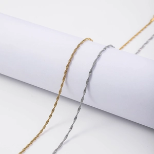 Detailed view of 18K gold and silver water wave twisted chains on a minimalist stand