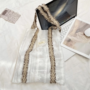 Detail of Suzakka floral lace tote showing textured fabric and woven shoulder strap