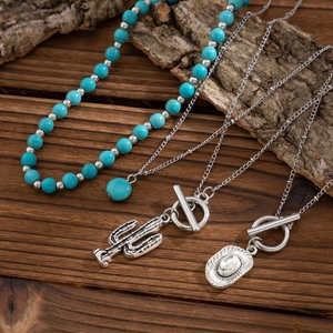 Detail of bohemian necklace set featuring turquoise beads, cactus and cowboy hat charms