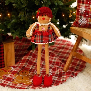 Standing gingerbread man plush doll with red plaid dress under a Christmas tree decor