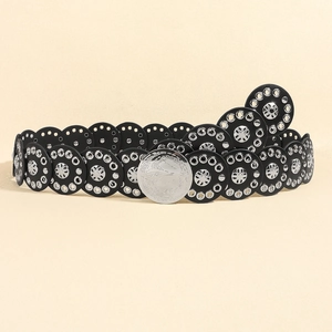 Detail of western punk style black belt with silver studs and large carved buckle