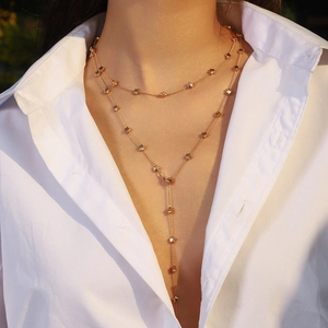 Detail of layered gold starfish and star necklace worn by a model in a white shirt