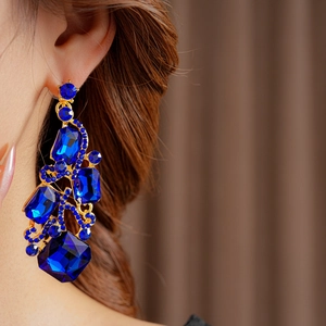 Close-up of vintage gold earrings with blue gemstones and diamonds on a model