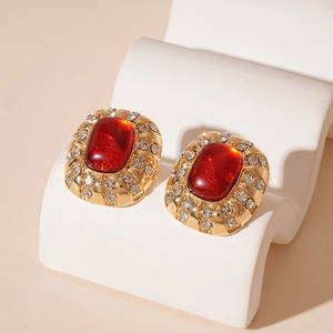 Gros plan de boucles d'oreilles vintage dorées avec résine rouge et cristaux pavés