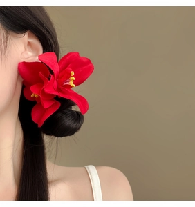 Vista detallada de una pinza para el pelo con orquídeas rojas en un peinado elegante