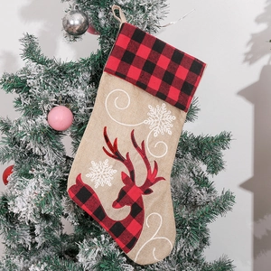 Christmas stocking hanging on a snow-covered tree with reindeer and snowflake embroidery