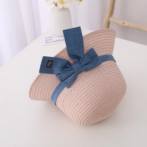 Detail of pink straw sun hat featuring a denim blue bow and handmade leather label