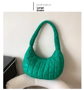 Close-up of a large green quilted puffer shoulder bag with glossy nylon texture