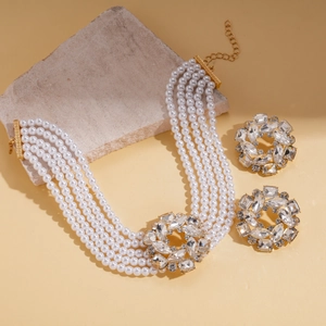 Elegant multi-layer pearl necklace and rhinestone stud earrings set on a stone display