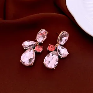Boucles d'oreilles gouttes dorées roses avec cristaux roses sur fond de velours sombre
