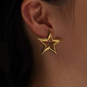 Minimalist gold hollow star stud earrings in polished stainless steel on female ear