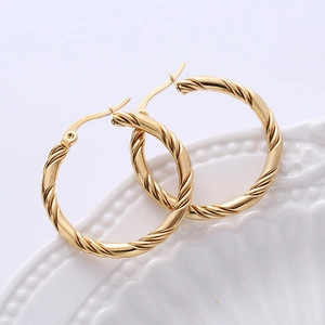 Detail of 30mm 18K gold plated twisted hoop earrings on white ceramic tray