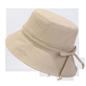 Détail d'un chapeau bob d'été avec texture plissée et nœud tissé décoratif avec breloque métal