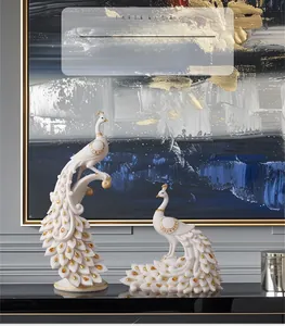 Close-up of white resin peacock figurines with gold hand-painted lines and amber gems