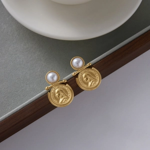 Detailed shot of gold coin earrings with pearl studs on a velvet jewelry tray