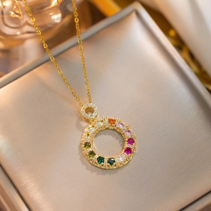 Golden titanium steel necklace with a colorful zircon donut pendant on a jewelry box