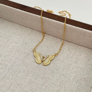 Detail of gold butterfly pendant with white zircon stones on linen tray backdrop