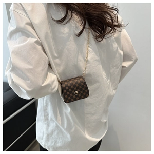 Detail of dark brown mini crossbody bag with circular pattern and gold chain strap