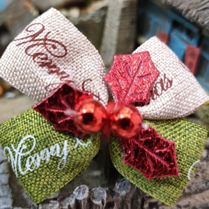 Macro detail of Christmas bow with Merry Christmas ribbon and red sequin leaf decor