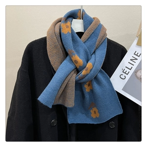 Detail of navy knit scarf with yellow flower patterns over a black double-breasted coat