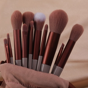 Close-up of 12 makeup brushes with red-brown handles in a brown fabric storage pouch
