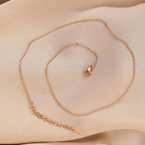 Detailed view of rose gold stainless steel O-chain necklace on soft silk fabric