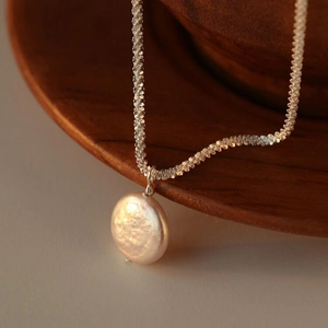 S925 sterling silver necklace with baroque pearl pendant on a twisted chain over a wooden bowl