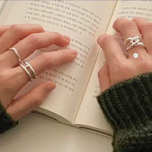 Detailed view of minimalist S925 silver layered rings on a knitted sweater background