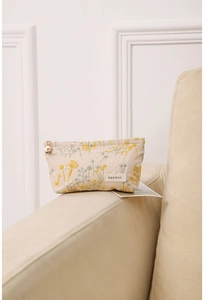 Détail de la trousse en lin avec broderie florale et tirette de zip fleur dorée