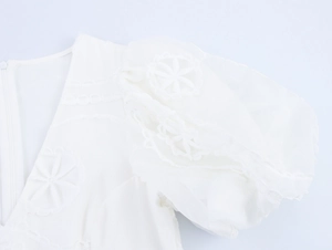 Détail de la broderie florale blanche et de la manche bouffante d'une robe de style français