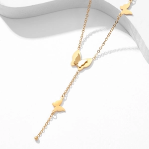Close-up of golden necklace with three butterfly charms on a white minimalist background