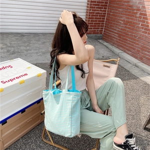 Vista exterior de un bolso tote de lona a cuadros azules y blancos con correa tejida azul