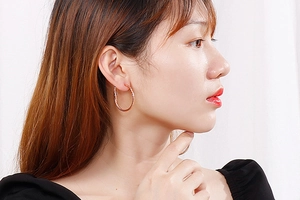 Close-up of rose gold stainless steel hoop earrings with twist texture on model