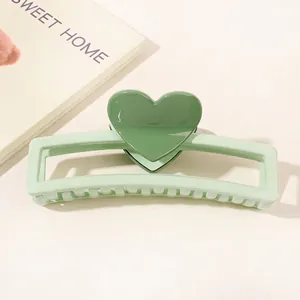 Detail of green heart hair claw clip with rectangular cutout and dual-tone acrylic design