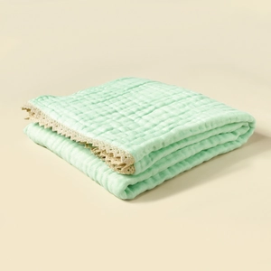 Detail of mint green cotton gauze baby blanket with waffle texture and lace trim