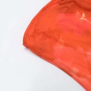 Vue macro détaillée du tissu en maille orange à imprimé floral avec une texture de couture