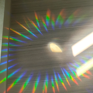 Vibrant rainbow light refraction on wood surface from crystal suncatcher prism pendant