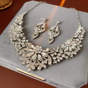 Macro shot of silver flower necklace and earrings set with clear crystals on velvet