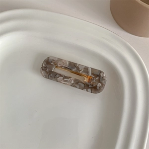 French vintage marble acetate hair clip on a white ceramic plate with a golden metal base