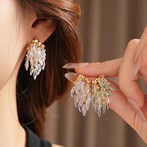 Détail de boucles d'oreilles pampilles dorées avec cristaux de zircone et reflets