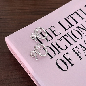 Silver hollow bowknot hoop earrings on a fashion book cover with minimalist aesthetic