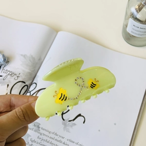 Pince à cheveux fleur vert pâle avec abeilles jaunes et strass tenue en main