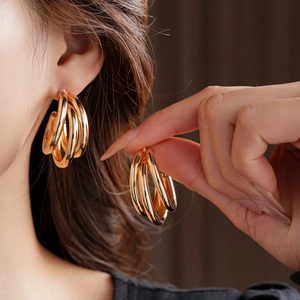 Gros plan de boucles d'oreilles dorées irrégulières multicouches en forme de C
