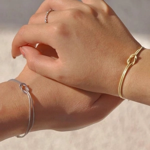 Detail of silver and gold knotted bangles and ring on wrist under natural sunlight