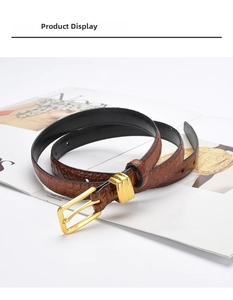Detail of brown crocodile pattern leather belt with gold metal buckle and dual loops