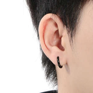 Close-up of minimalist black stainless steel hoop earring worn on a model's earlobe